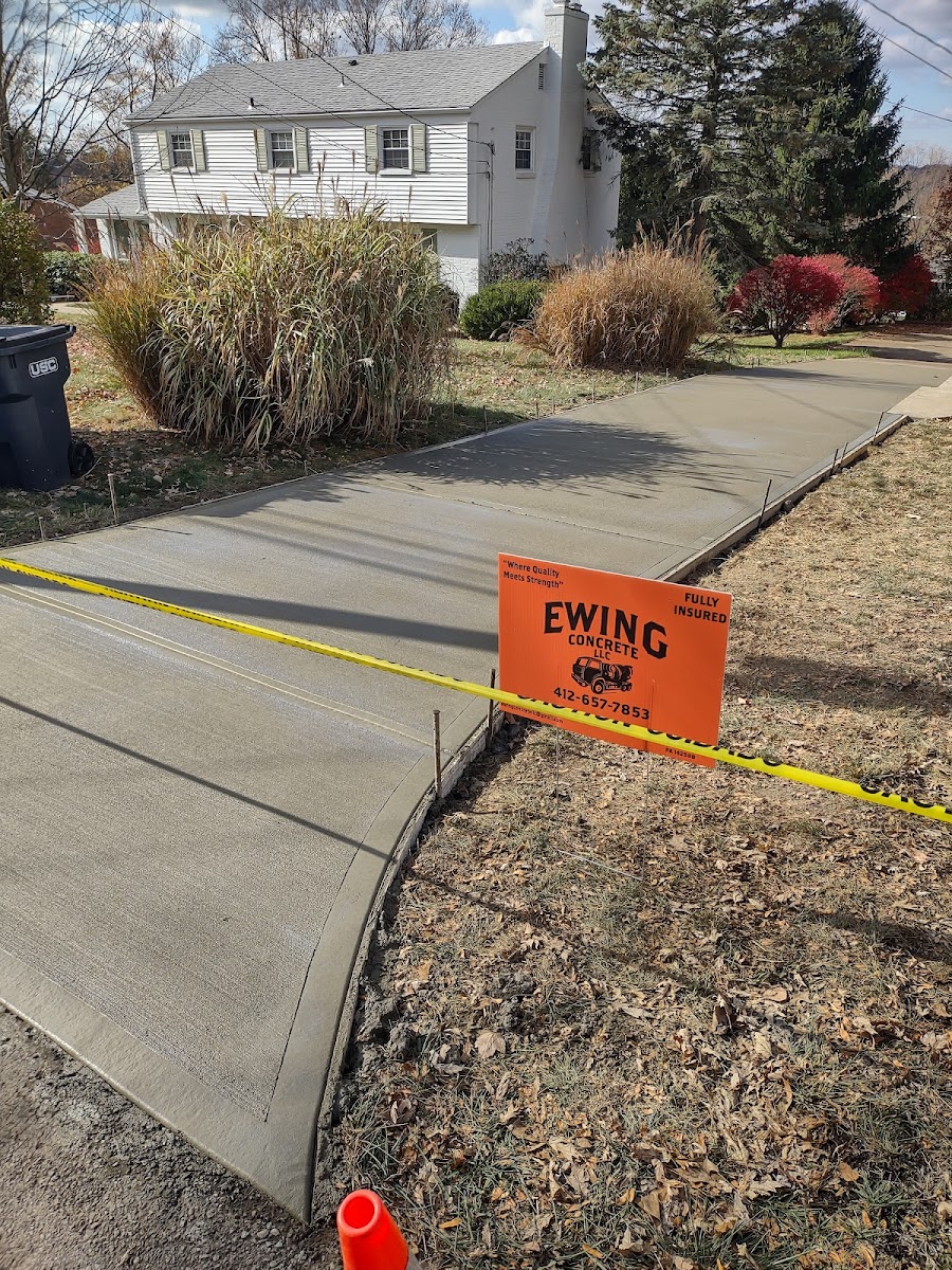 Freshly poured concrete sidewalk with the Ewing Concrete job sign